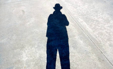 un ombra d'uomo si allunga sull'asfalto